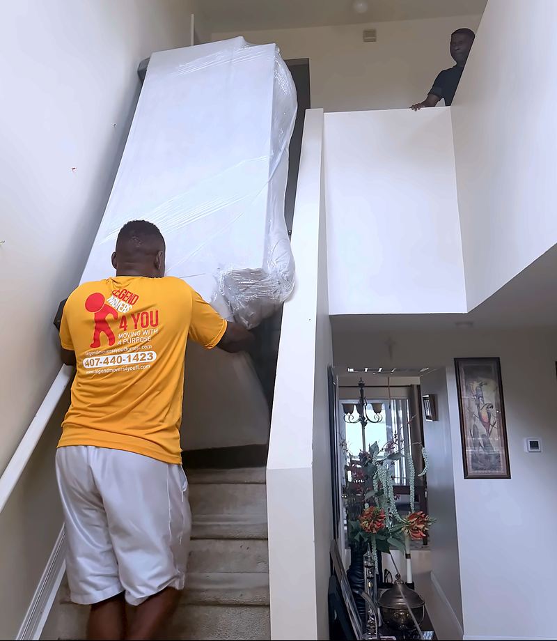 Legend Movers 4 You mover carrying a fully wrapped piece of furniture up the stairs of an Orlando home