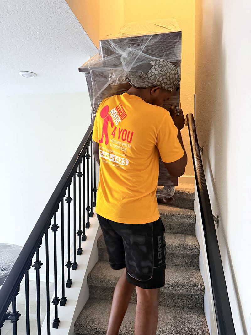 Mover carrying a wrapped dresser upstairs