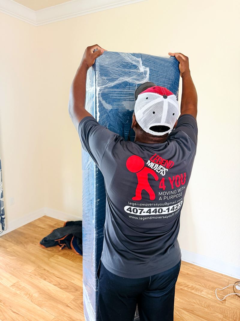 Mover carrying a mattress wrapped for the move