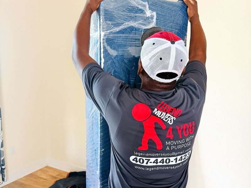 Mover carrying a mattress wrapped for the move