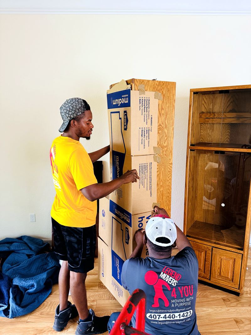 Two movers protecting a wooden cabinet with cardboard