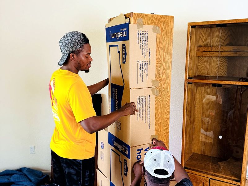 Two movers protecting a wooden cabinet with cardboard