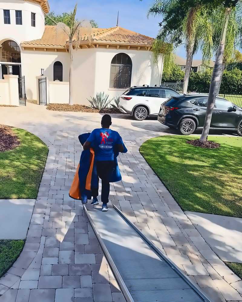 Legend Movers 4 You mover carrying moving blankets along the truck ramp outside a Central Florida home