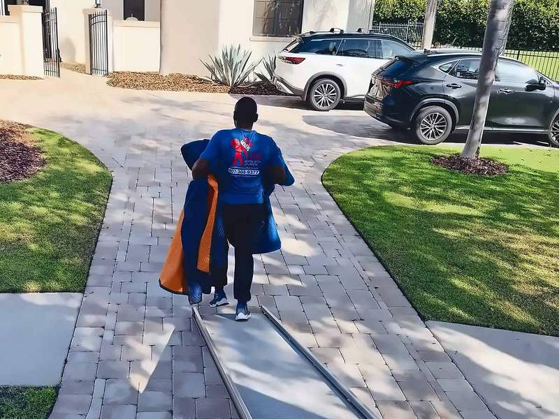 Legend Movers 4 You mover carrying moving blankets along the truck ramp outside a Central Florida home